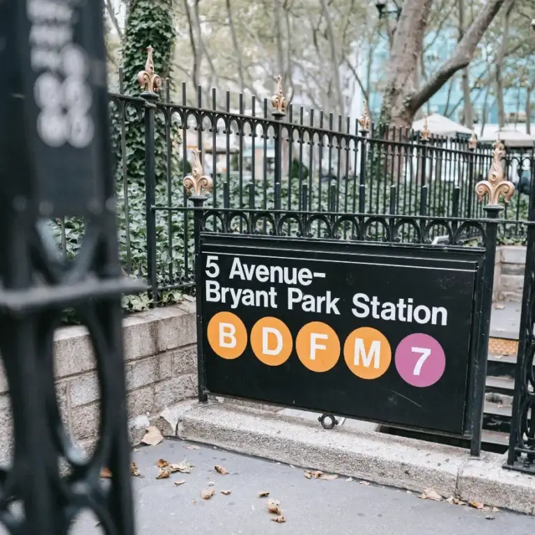 Black subway entrance sign for 5 Avenue-Bryant Park Station mounted on a wrought iron fence, optimized for A-frame signs Brisbane style outdoors.
