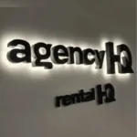 Illuminated 3D backlit wall logo for agencyHQ and rentalHQ mounted on a smooth office wall, showcasing signage north lakes designs.