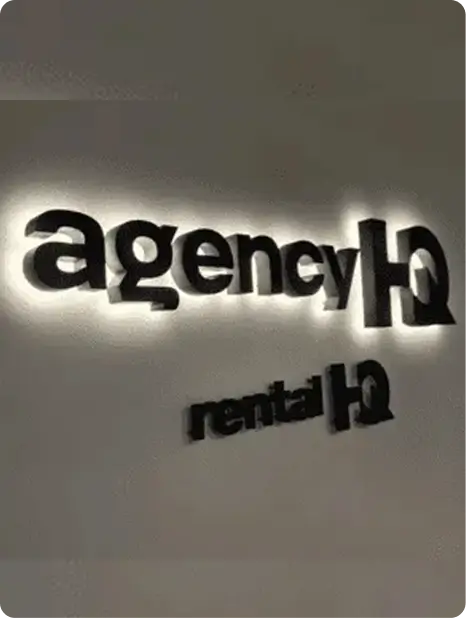 Illuminated 3D backlit wall logo for agencyHQ and rentalHQ mounted on a smooth office wall, showcasing signage north lakes designs.
